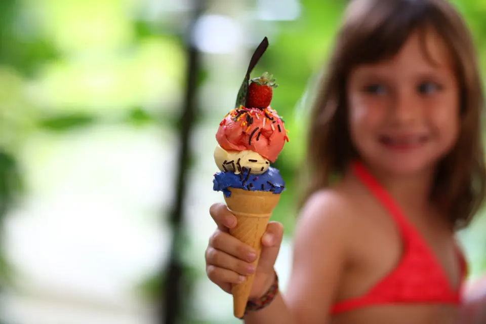 Child holding a colorful ice cream cone near the pool at Bahia Principe Grand Coba