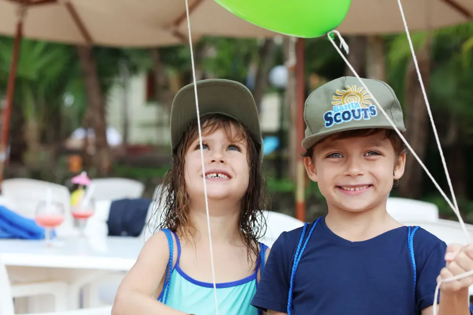 Two children holding balloons and smiling at Bahia Principe Grand Coba resort