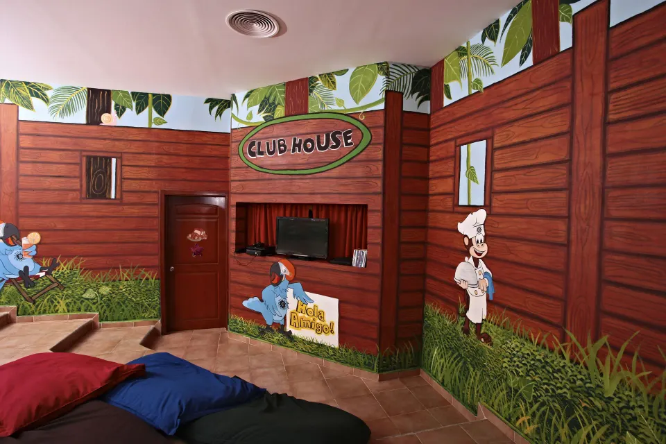 Clubhouse playroom with wood-themed murals and TV nook at Bahia Principe Grand Coba