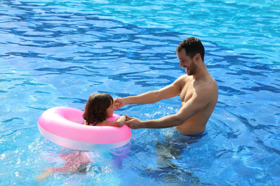 Father playing with child in a turquoise resort pool at Bahia Principe Grand Coba