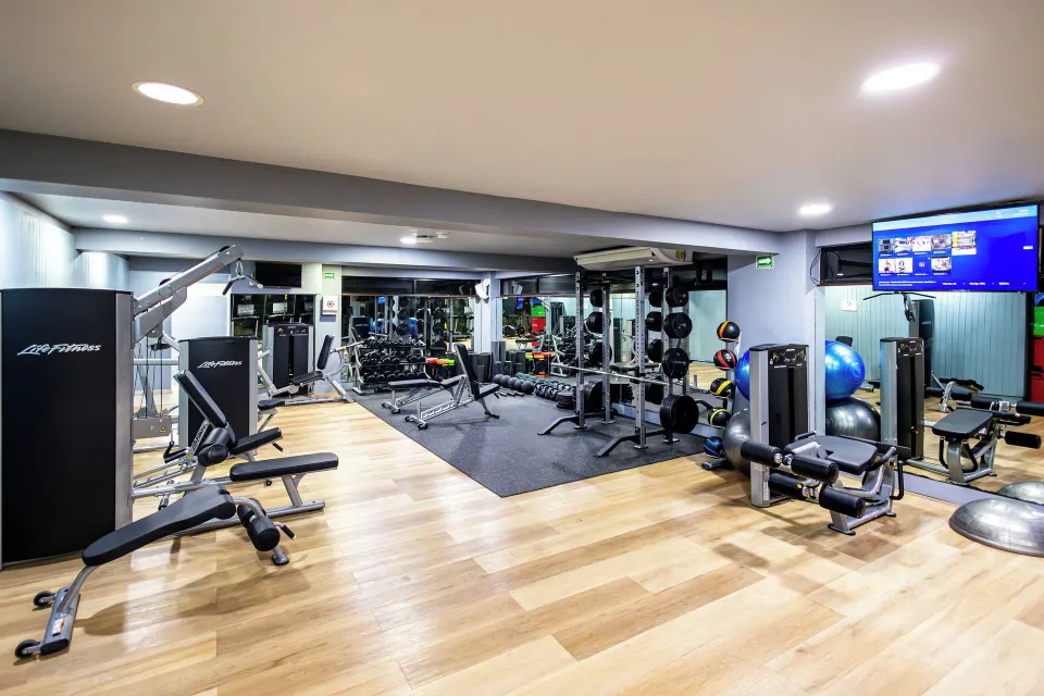Well-equipped indoor fitness center with weight machines and free weights at Bahia Principe Grand Coba.