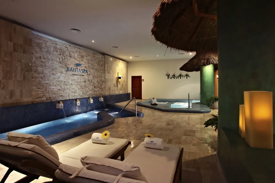 Relaxation area with loungers and spa pools in an indoor spa at Bahia Principe Grand Coba.