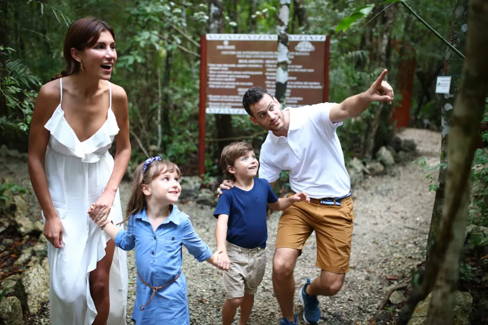 Family walking on a jungle trail with an interpretive sign at Bahia Principe Grand Coba
