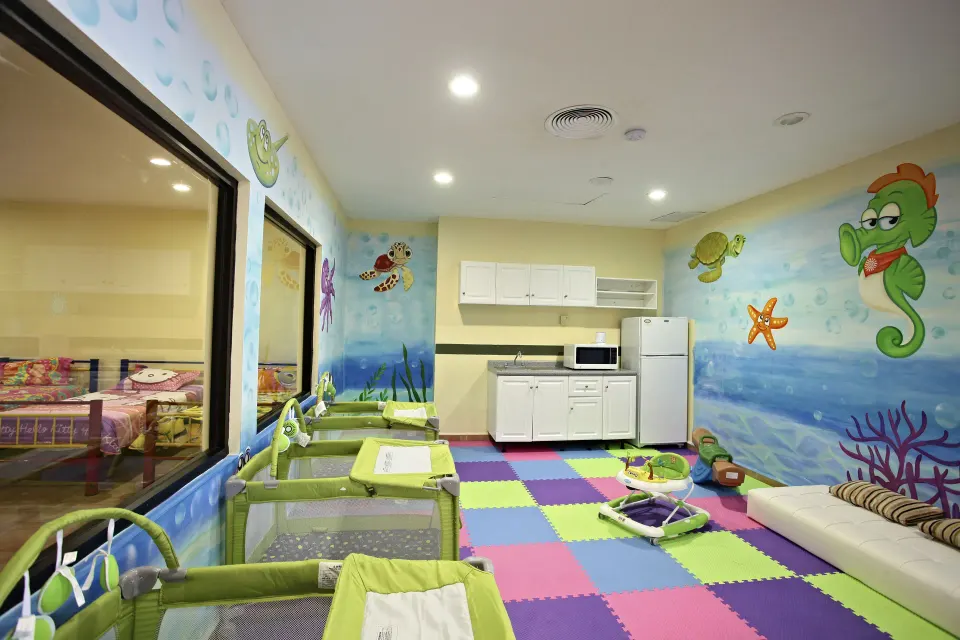 Colorful nursery room with cribs and kitchenette at Bahia Principe Grand Coba
