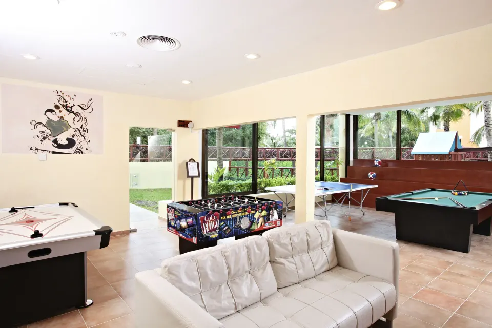 Open kids play area with foosball, pool table and large windows at Bahia Principe Grand Coba