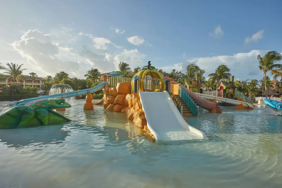 Multiple gentle slides and a central play mound in the children's pool at Bahia Principe Grand Coba