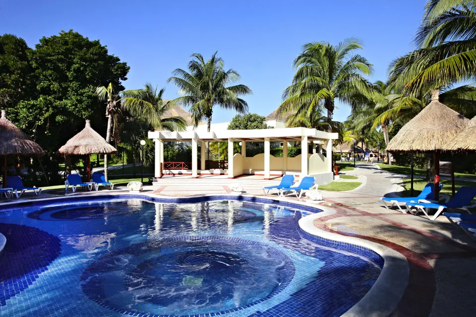Small circular pool spa and shaded pergola with loungers at Bahia Principe Grand Coba