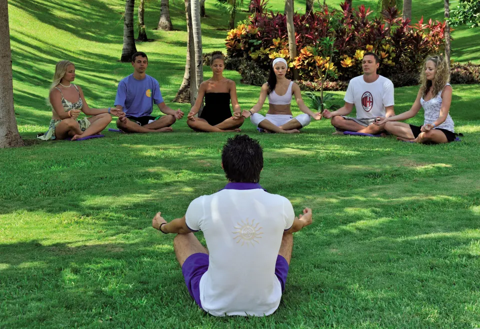 Outdoor yoga class on the grassy resort grounds at Bahia Principe Grand Coba.