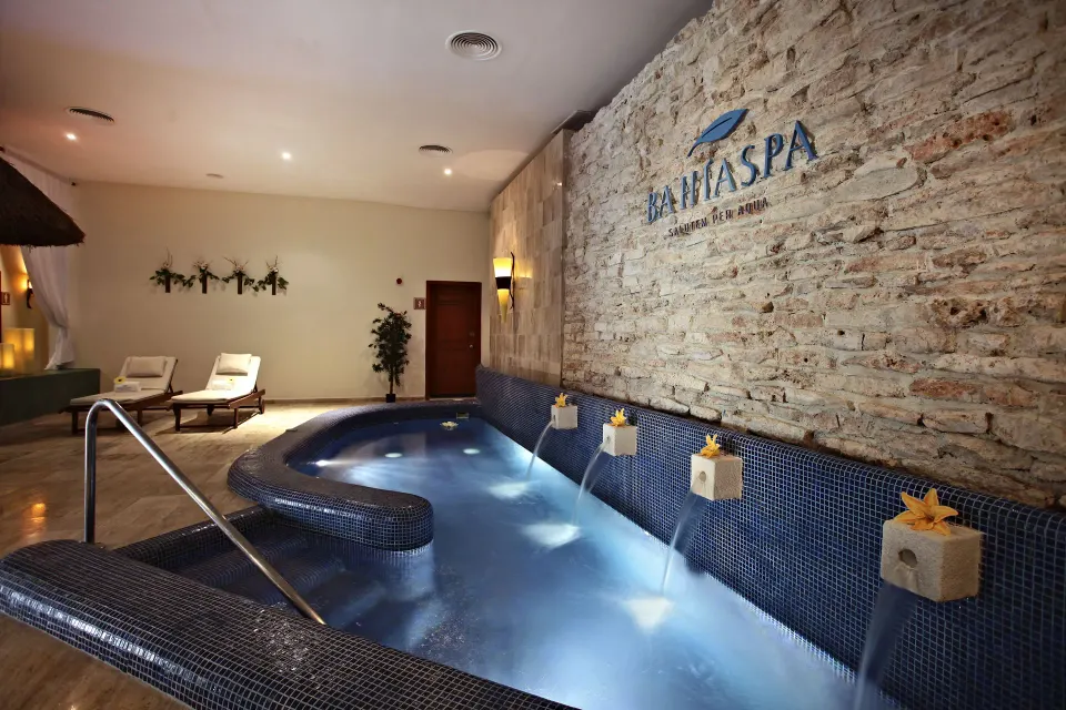 Tiled spa hydrotherapy pool with cascading water jets and decorative wall at Bahia Principe Grand Coba.