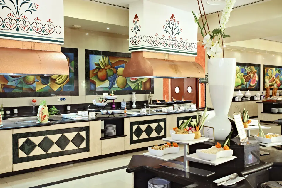 Close-up of buffet counters with decorative artwork and service stations at Bahia Principe Grand Coba