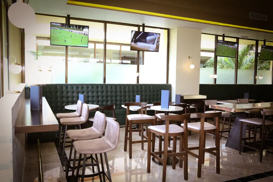 Casual dining area with high stools and TVs at Bahia Principe Grand Coba