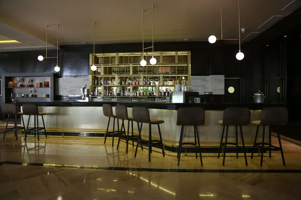Sleek indoor bar with stools and backlit shelves at Bahia Principe Grand Coba