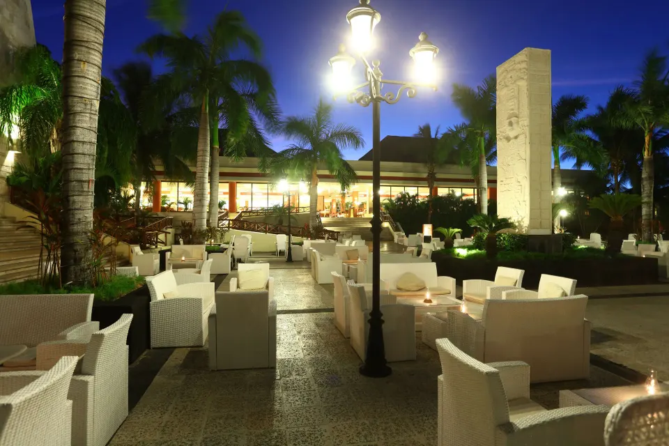Nighttime courtyard lounge seating under palm trees at Bahia Principe Grand Coba