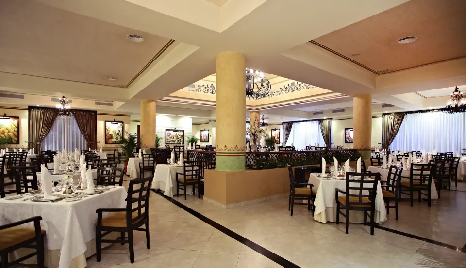 Large formal dining room with many set tables at Bahia Principe Grand Coba