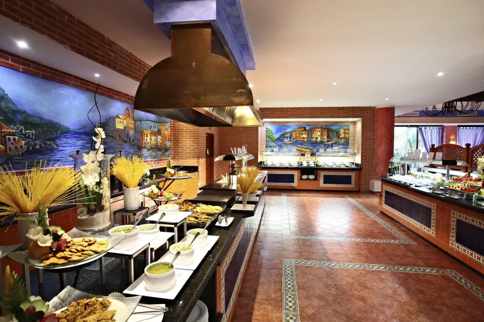 Buffet island and hot-food stations with painted murals at Bahia Principe Grand Coba