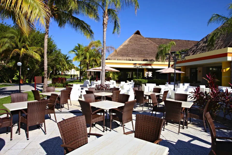 Sunny outdoor dining area with wicker chairs at Bahia Principe Grand Coba