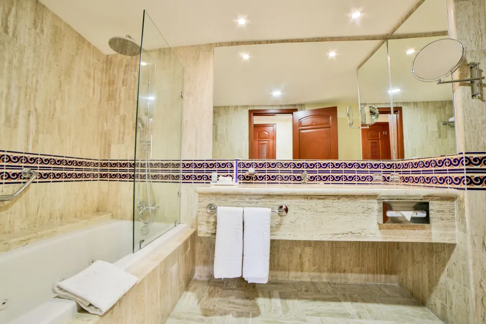 Junior Suite Superior bathroom with bathtub, overhead shower and large mirror at Bahia Principe Grand Coba