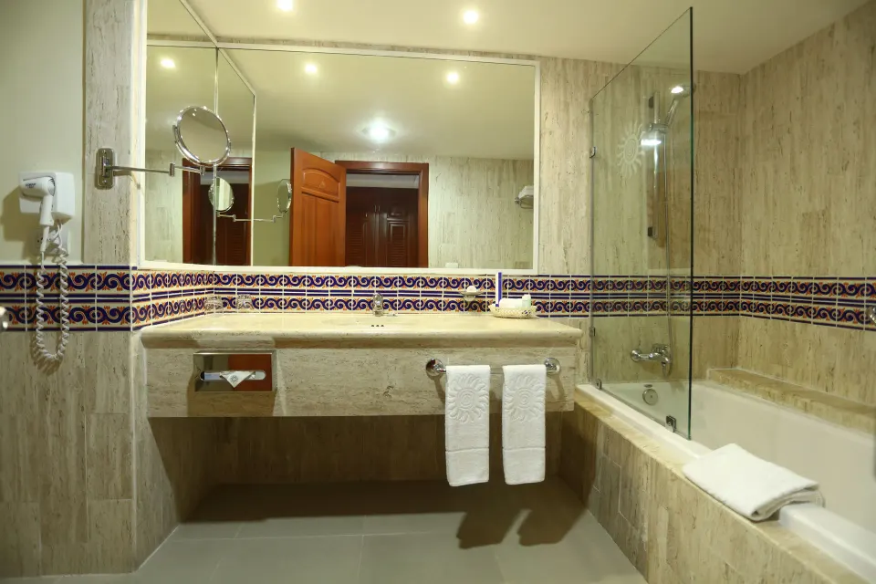 Junior Suite Superior bathroom vanity and bathtub with glass screen at Bahia Principe Grand Coba