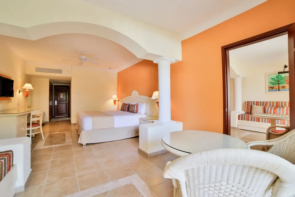 Junior Suite Superior bedroom and sitting area with arched divider at Bahia Principe Grand Coba