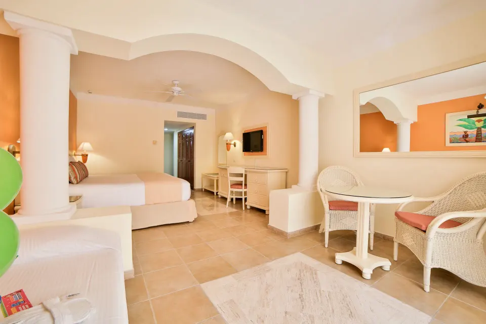 Junior Suite Superior wide view showing bed, desk and round dining table at Bahia Principe Grand Coba