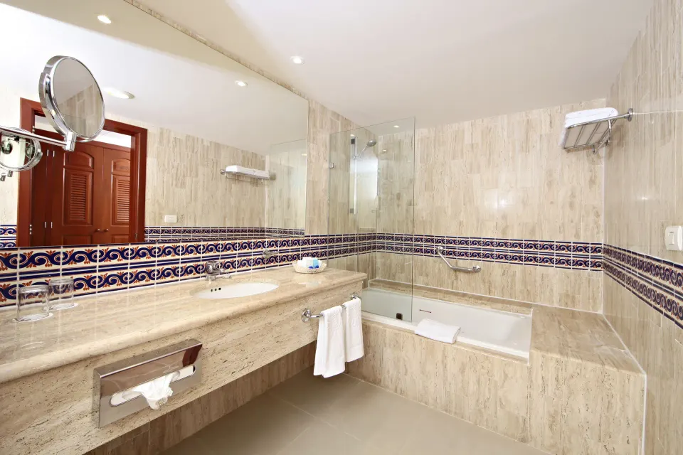 Junior Suite Superior marble vanity and bathtub corner with towel rack at Bahia Principe Grand Coba
