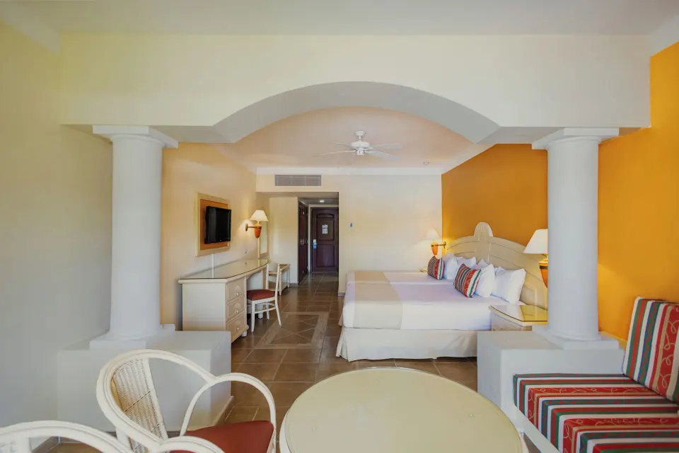 Suite interior looking toward entrance with two beds and arched column details at Bahia Principe Grand Coba