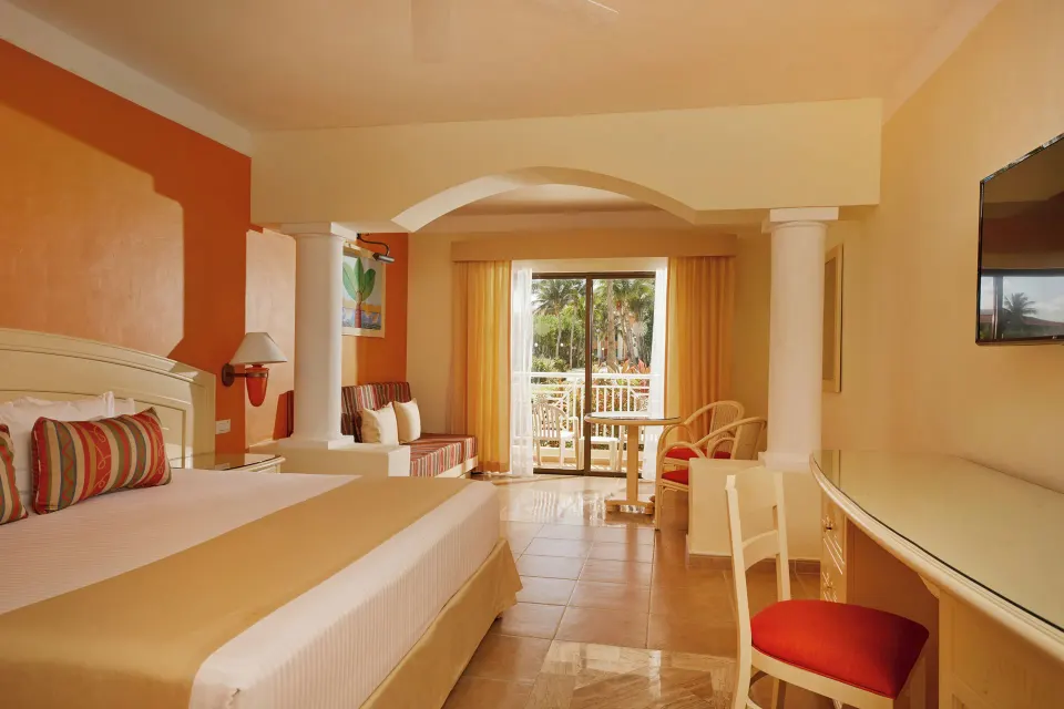 Junior Suite bedroom with king-size bed, desk and balcony at Bahia Principe Grand Coba