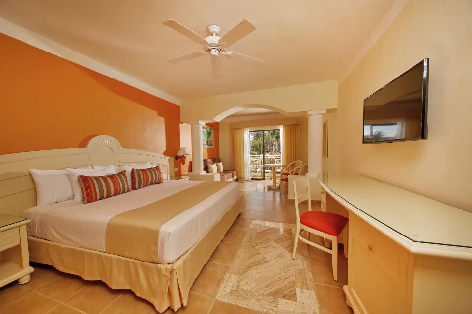 Junior Suite king bed, seating area and balcony at Bahia Principe Grand Coba