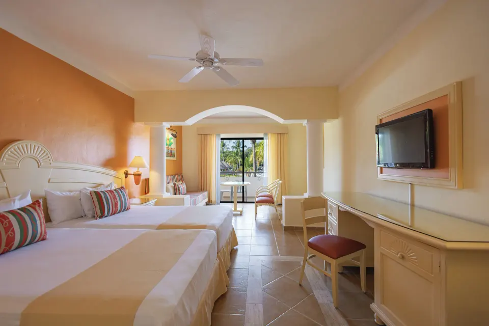 Junior Suite with two double beds, seating area and balcony at Bahia Principe Grand Coba