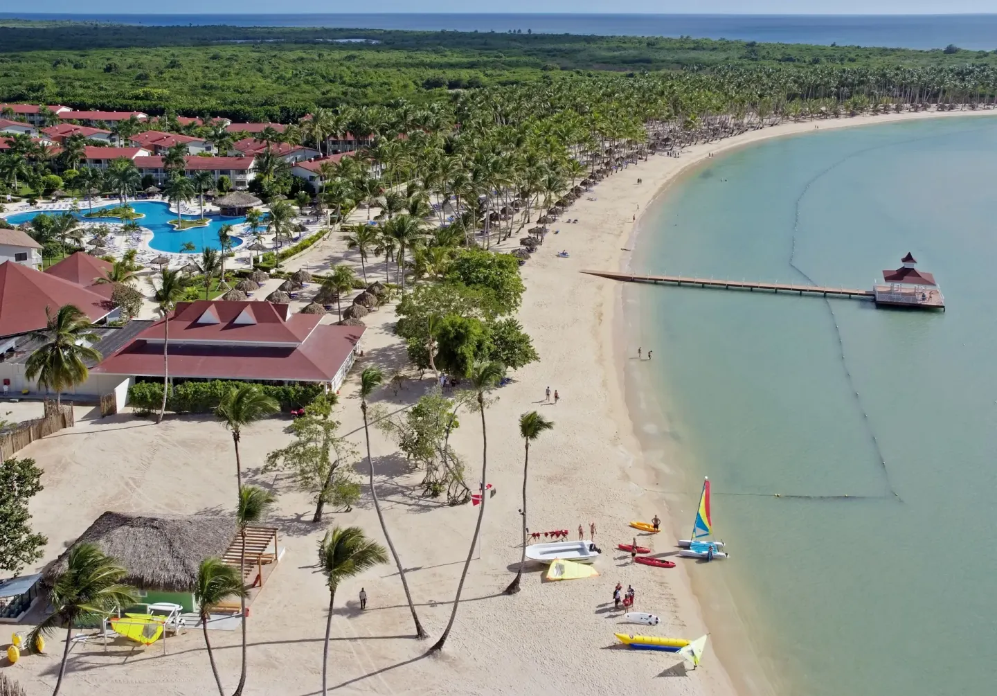 Aerial view of the beach, pier, pool, and resort buildings at Bahia Principe Grand La Romana.