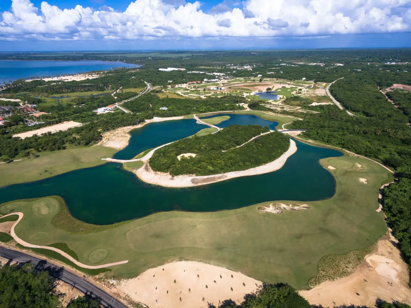 Aerial view of golf greens, lagoons, and coastline near Bahia Principe Grand La Romana.