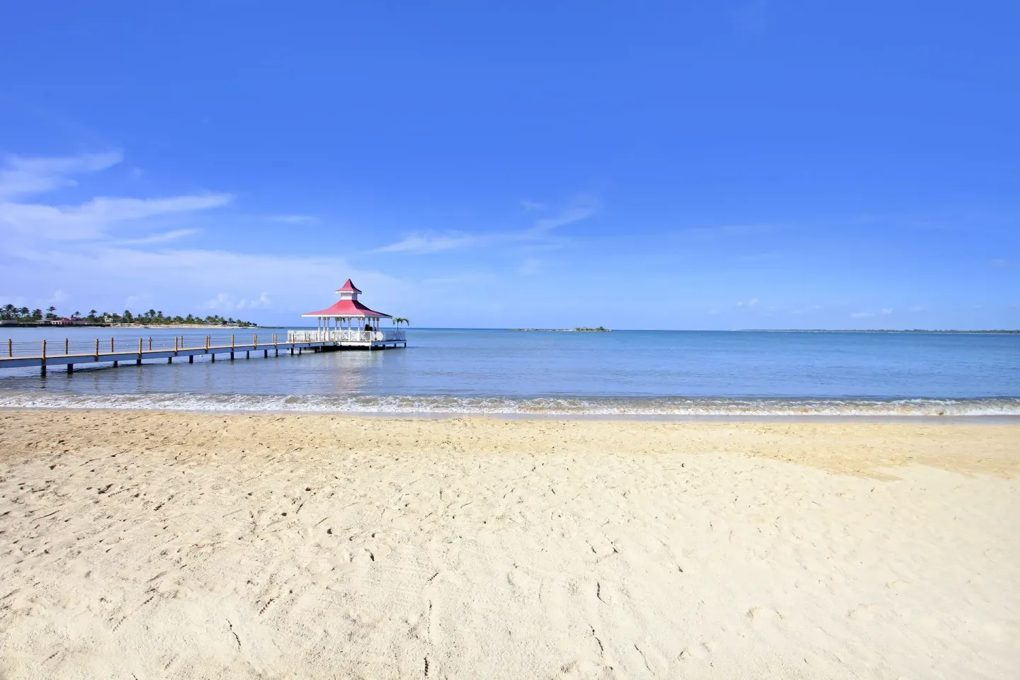 Sandy beach and pier over calm water at Bahia Principe Grand La Romana.
