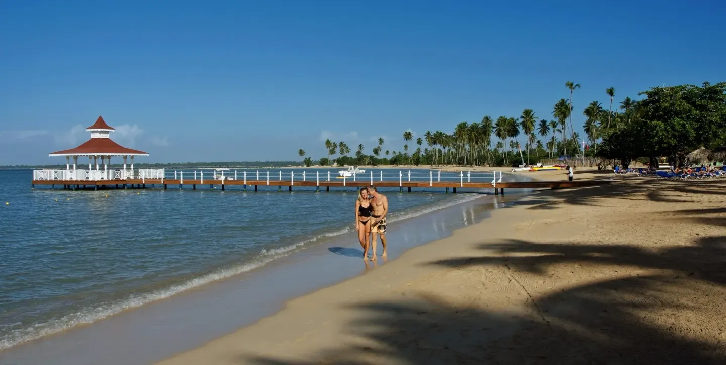 Sandy beach and white pier over calm water at Bahia Principe Grand La Romana.