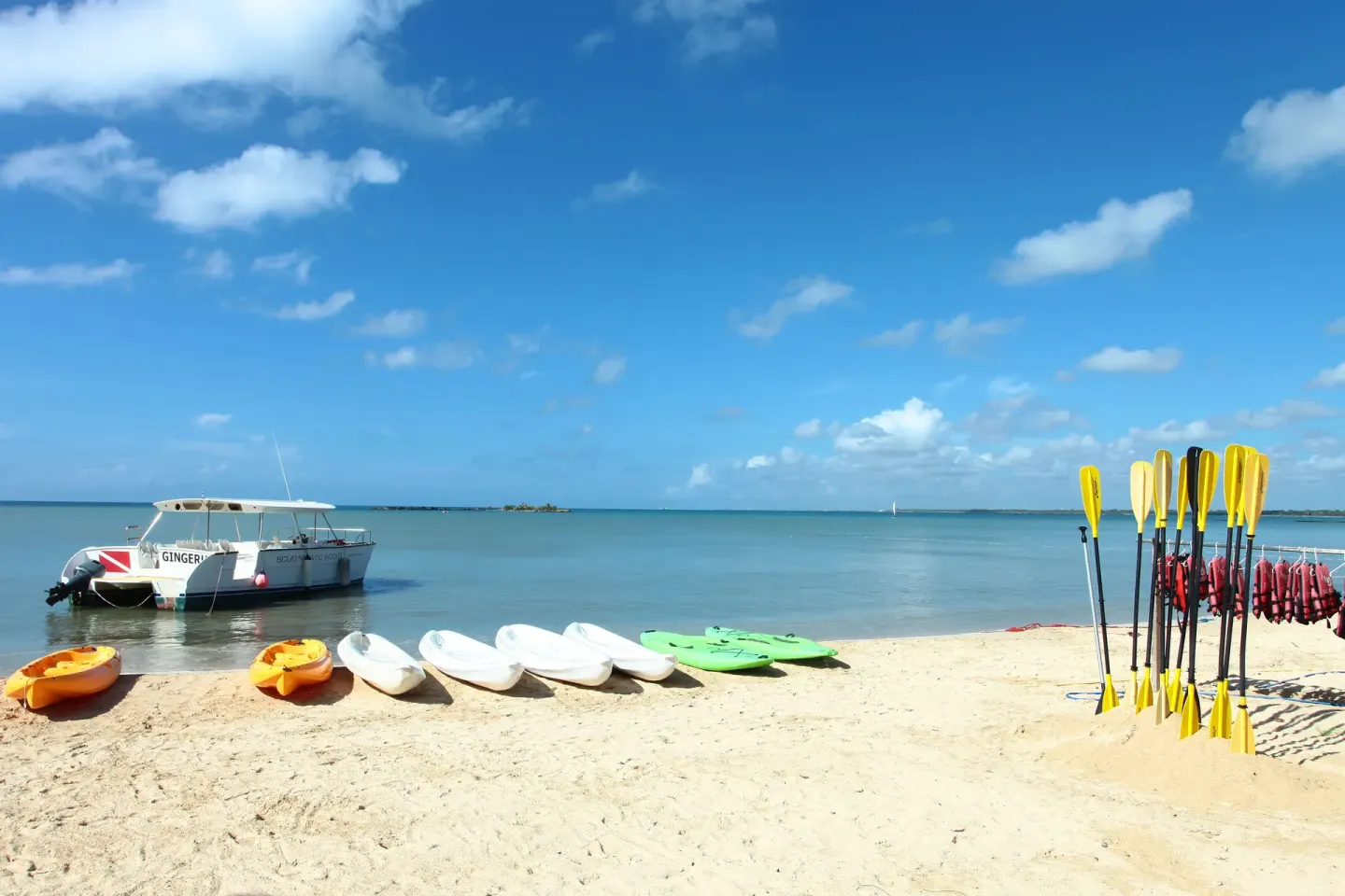 Kayaks, paddles, life vests, and a boat on the beach at Bahia Principe Grand La Romana.