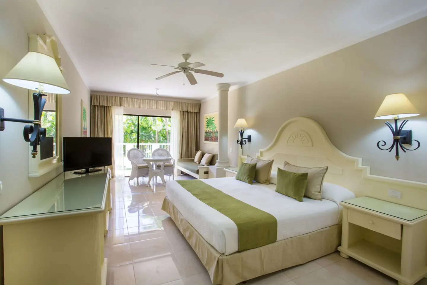 Guest room at Bahia Principe Grand La Romana with a king bed, TV, seating area and balcony doors.