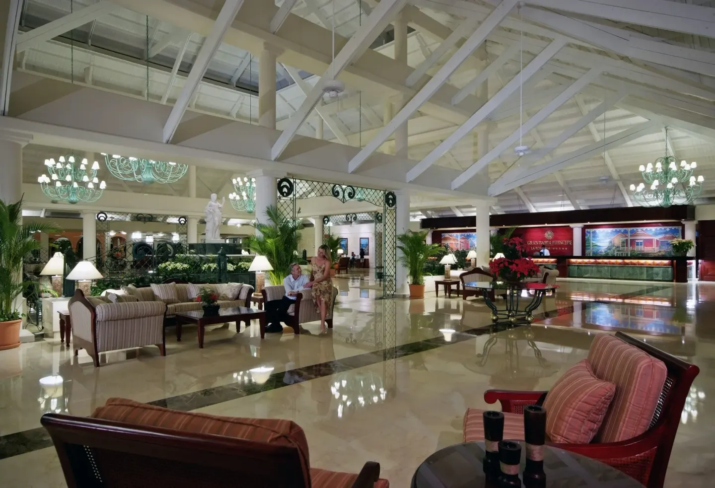Lobby lounge at Bahia Principe Grand La Romana with sofas, chandeliers, columns and reception desks.