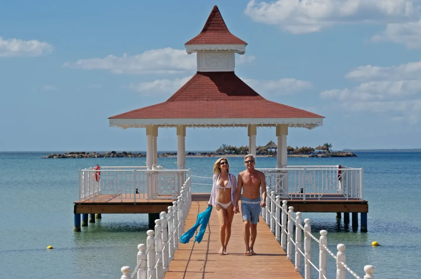 Couple walking on the pier toward the gazebo at Bahia Principe Grand La Romana.