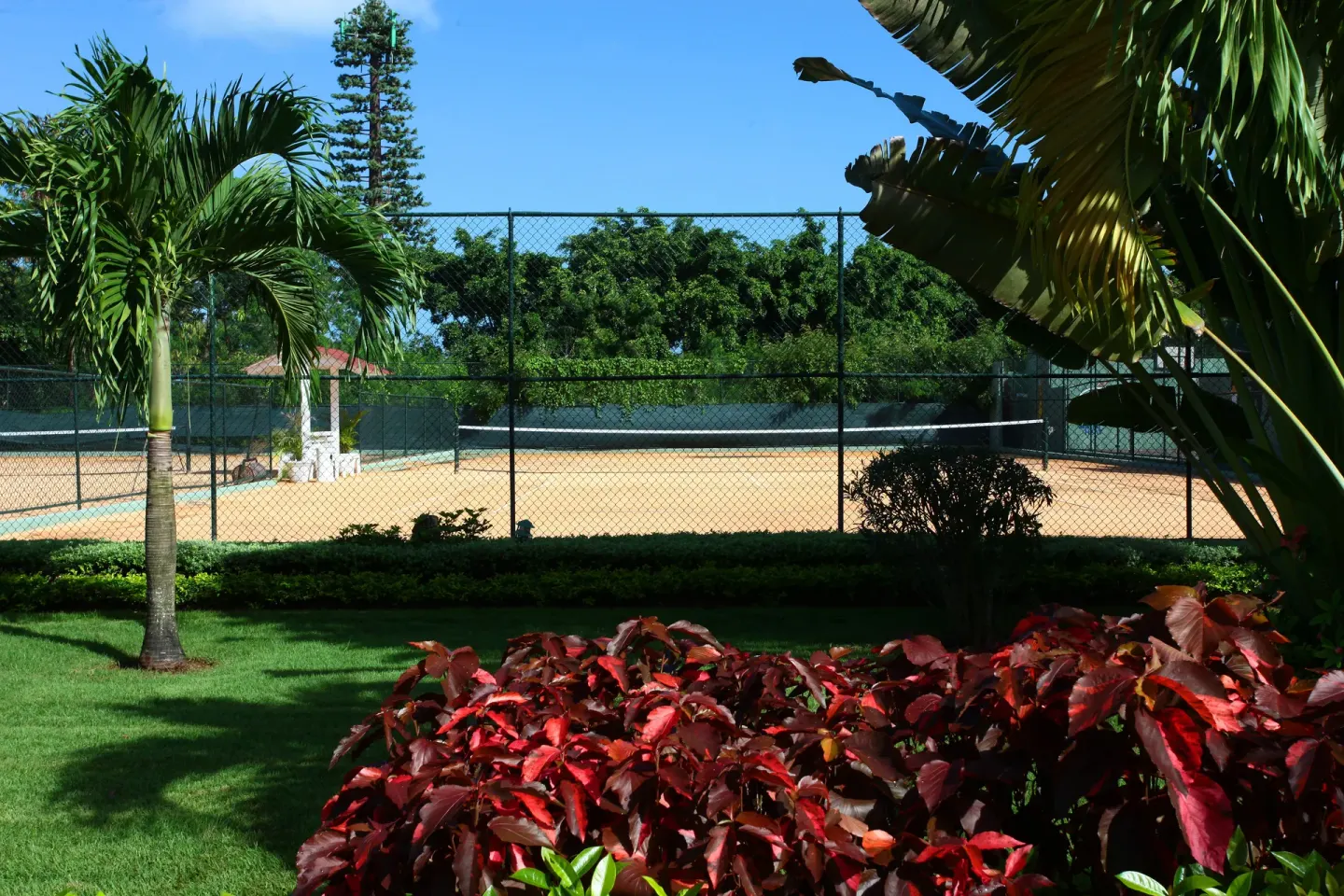 Tennis court behind tropical gardens at Bahia Principe Grand La Romana.
