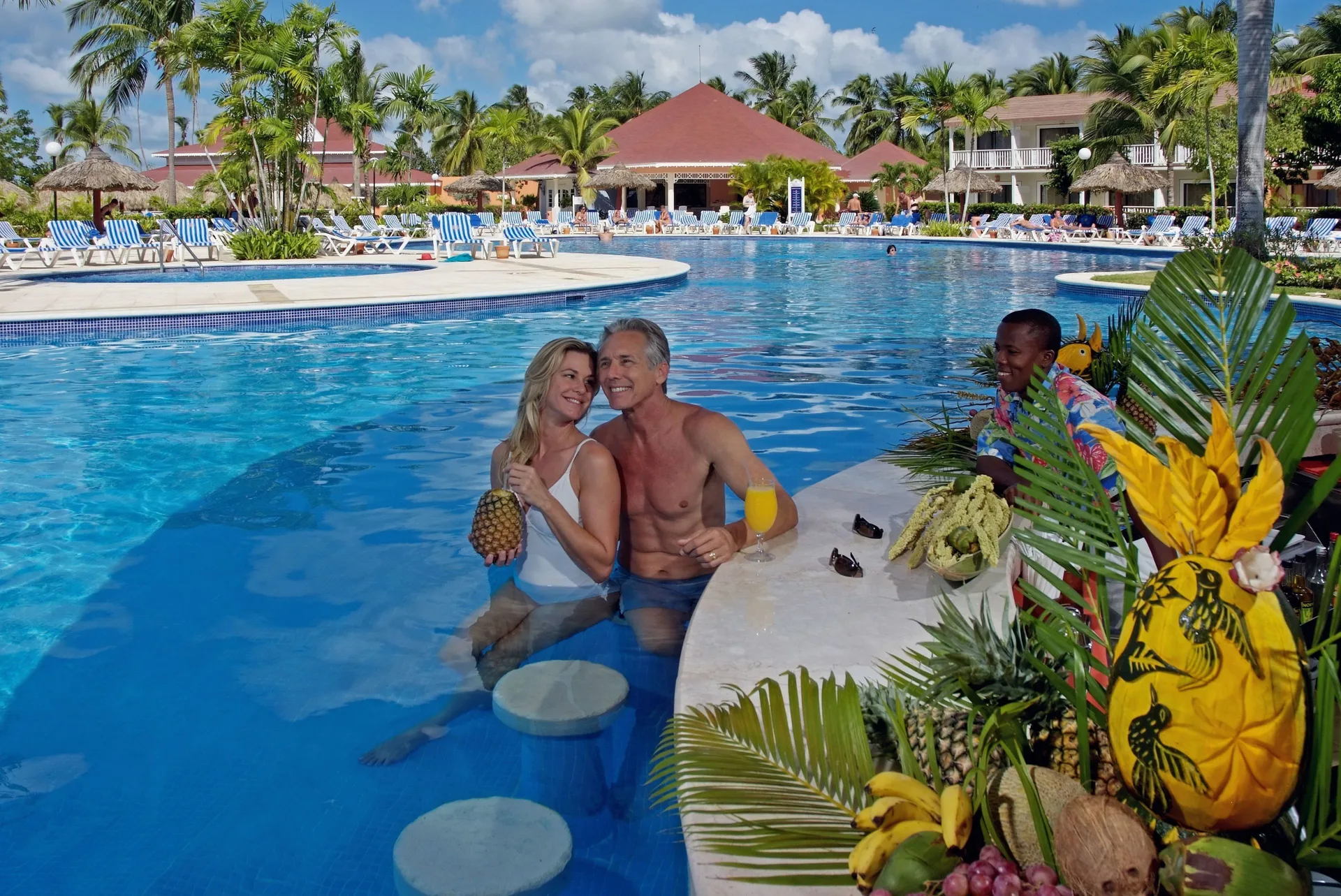 Swim-up pool bar with guests and tropical fruit at Bahia Principe Grand La Romana.
