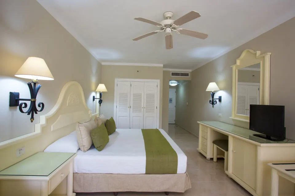 Junior Suite Superior king bed facing dresser and TV at Bahia Principe Grand La Romana.