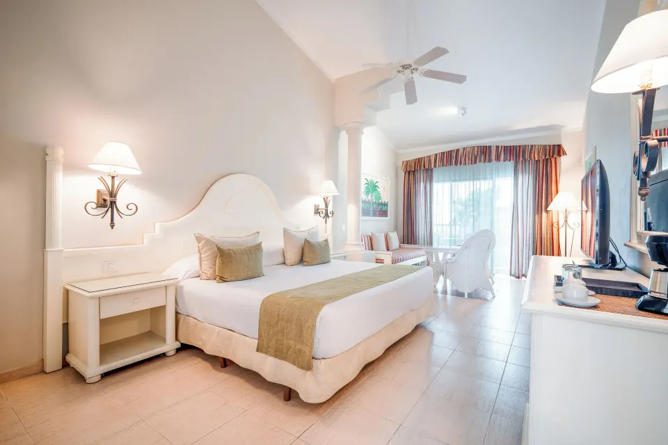 Junior Suite king bed and sitting area at Bahia Principe Grand La Romana.