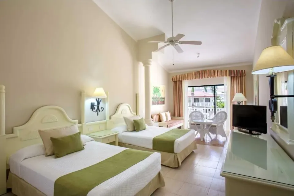 Junior Suite with two beds, TV and lounge area at Bahia Principe Grand La Romana.