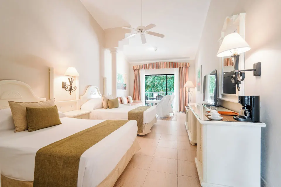 Junior Suite two-bed layout with TV and balcony doors at Bahia Principe Grand La Romana.