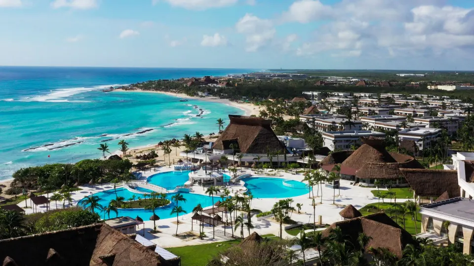 Aerial view of the resort pools, palapas and turquoise sea at Bahia Principe Grand Tulum