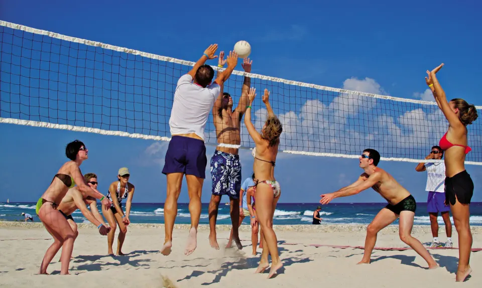 Group of people playing beach volleyball on a sunny beach at Bahia Principe Grand Tulum