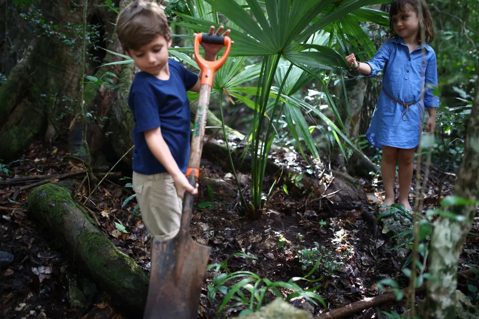 Two children exploring a shaded jungle-like garden area at Bahia Principe Grand Tulum