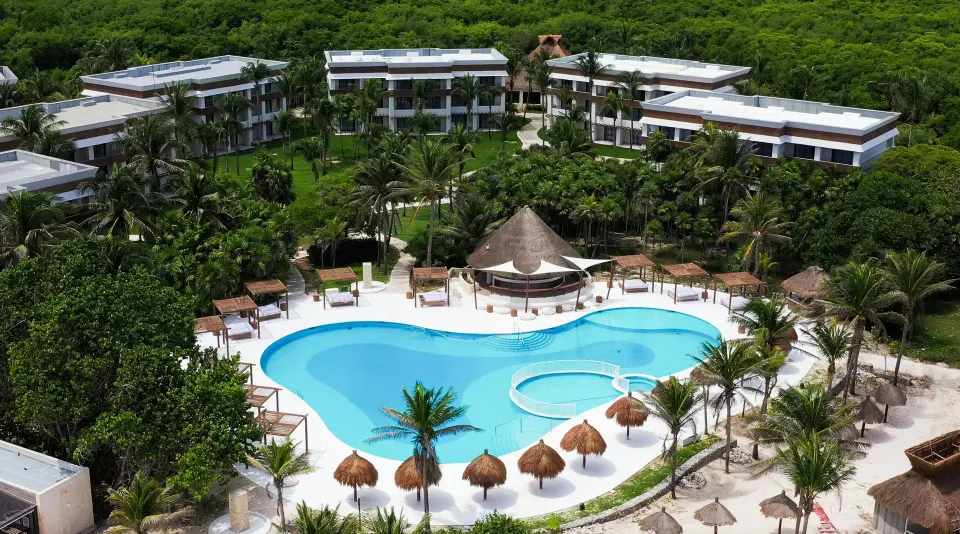 Heart-shaped pool with surrounding cabanas and palm trees at Bahia Principe Grand Tulum