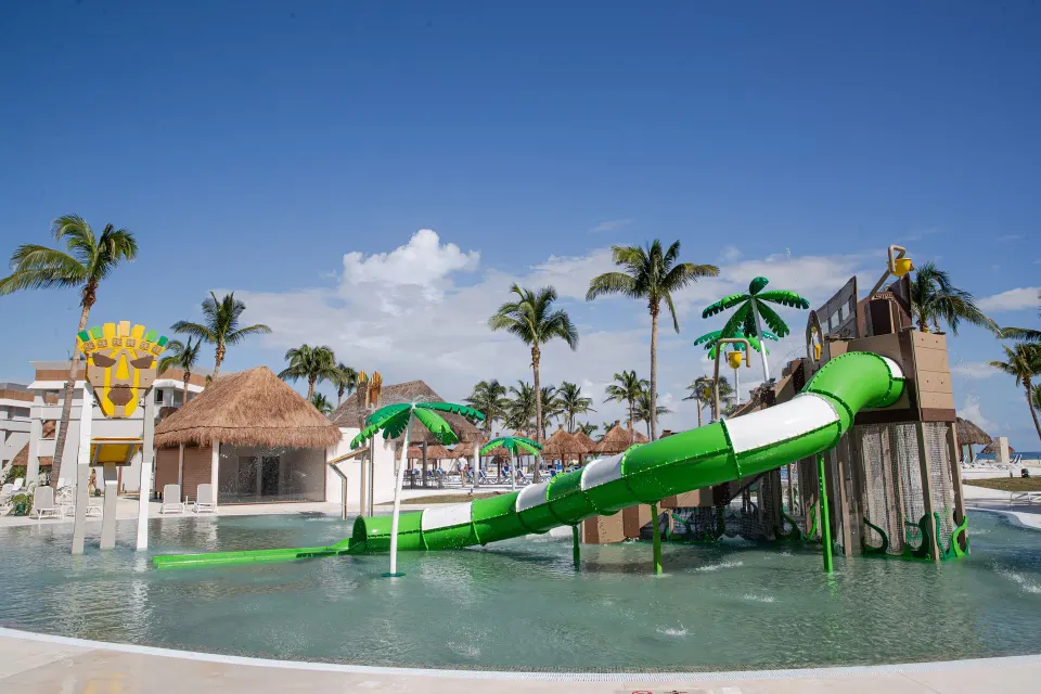 Green spiral water slide and play features in the resort children's pool at Bahia Principe Grand Tulum
