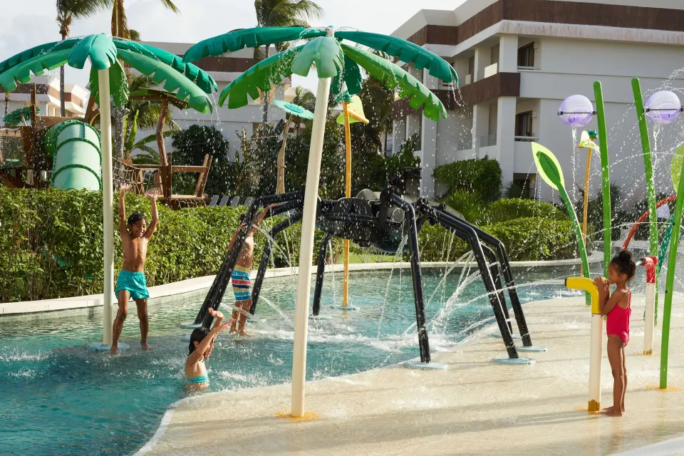 Children playing under water sprays and palm-shaped features at Bahia Principe Grand Tulum