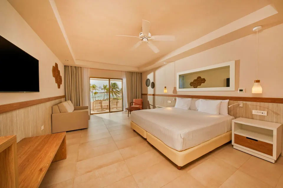 Modern king room with seating area and ocean view balcony at Bahia Principe Grand Tulum